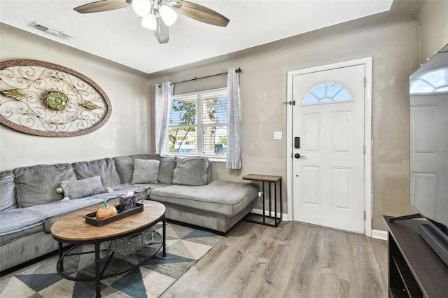 living room with light hardwood / wood-style floors, ceiling fan, and a healthy amount of sunlight