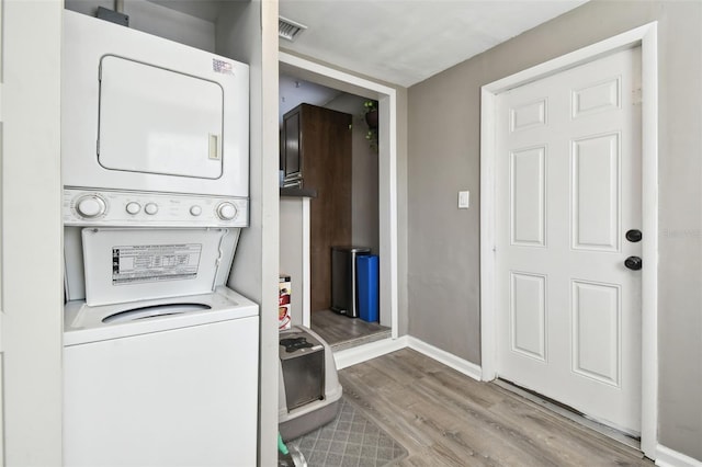 laundry room featuring stacked washer and dryer and light hardwood / wood-style floors