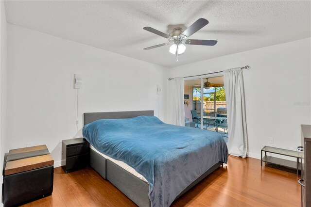 bedroom featuring hardwood / wood-style flooring, ceiling fan, access to exterior, and a textured ceiling