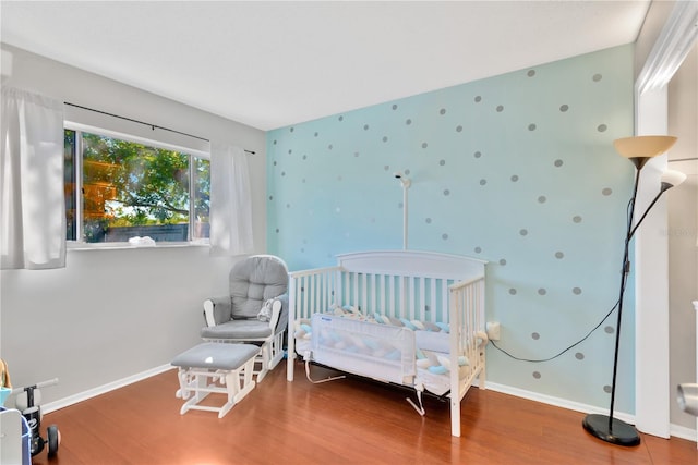 bedroom with hardwood / wood-style floors and a crib