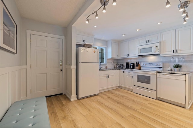 kitchen featuring white cabinetry, light wood-type flooring, white appliances, and backsplash