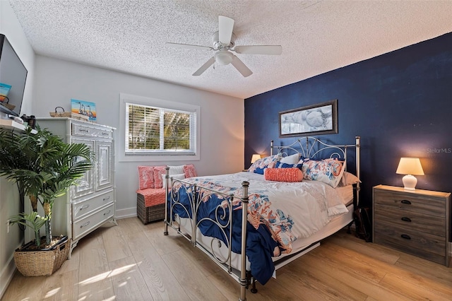 bedroom with ceiling fan, a textured ceiling, and light wood-type flooring