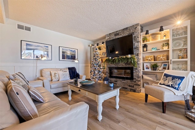 living room with a fireplace, a textured ceiling, and hardwood / wood-style flooring