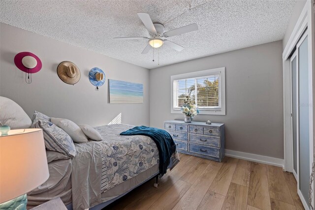 bedroom featuring a textured ceiling, light wood-type flooring, a closet, and ceiling fan