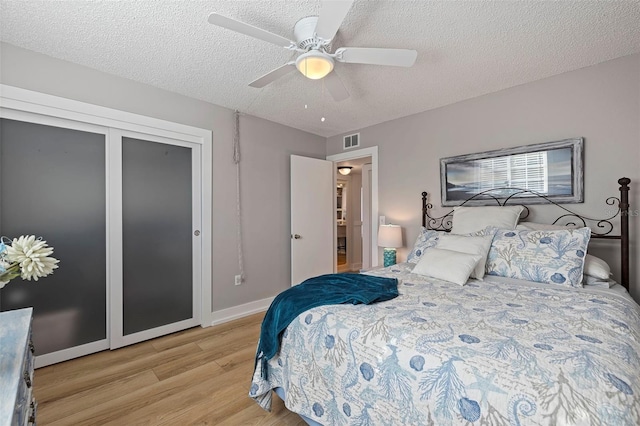 bedroom with ceiling fan, a textured ceiling, and light hardwood / wood-style flooring