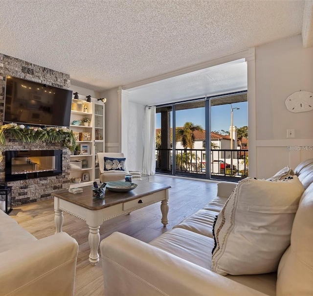 living area with a fireplace, wood finished floors, wainscoting, and a textured ceiling