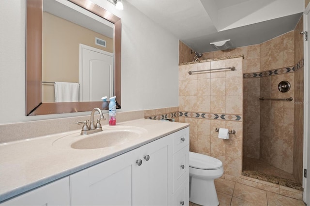 bathroom with tile patterned flooring, vanity, tiled shower, and tile walls