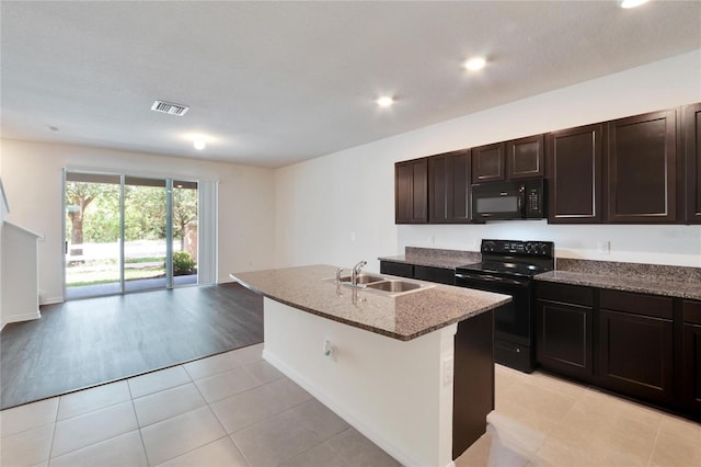 kitchen featuring dark brown cabinetry, sink, light hardwood / wood-style floors, a center island with sink, and black appliances