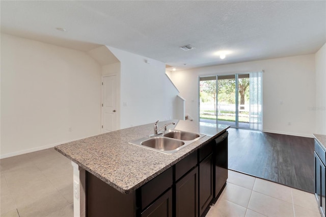 kitchen with dishwasher, sink, a textured ceiling, an island with sink, and dark brown cabinets