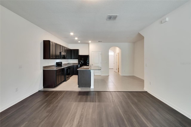 kitchen with a textured ceiling, a center island, stainless steel appliances, and light hardwood / wood-style flooring