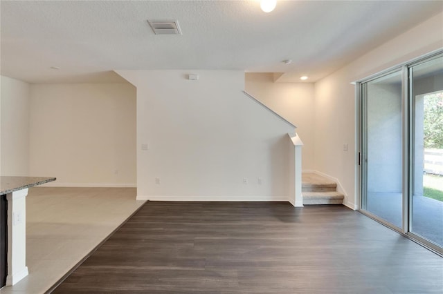 unfurnished living room featuring a textured ceiling and dark hardwood / wood-style floors