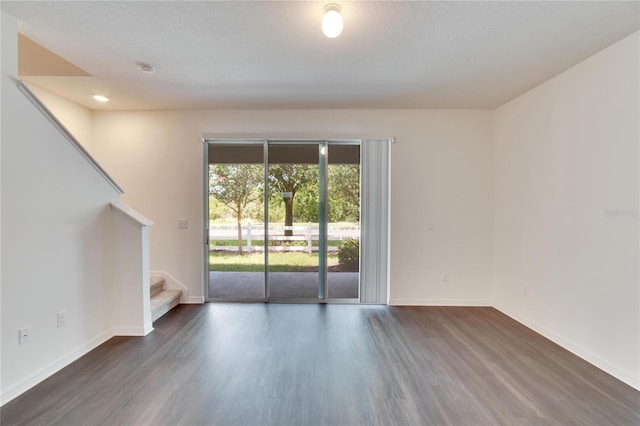 empty room with a textured ceiling and dark hardwood / wood-style floors