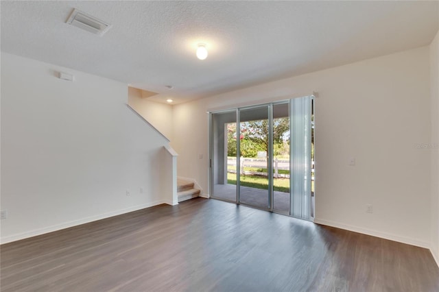 spare room with dark wood-type flooring and a textured ceiling