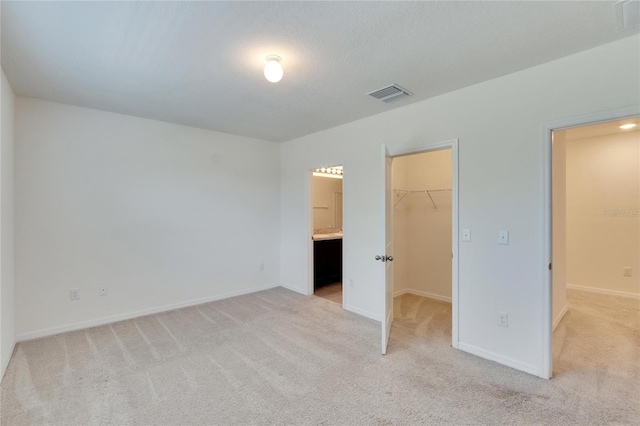 unfurnished bedroom with light carpet, a walk in closet, and a closet