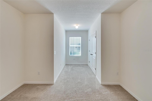 hallway featuring a textured ceiling and light colored carpet