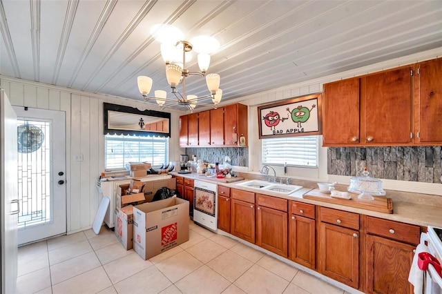 kitchen featuring wood walls, white range, sink, light tile patterned floors, and a chandelier