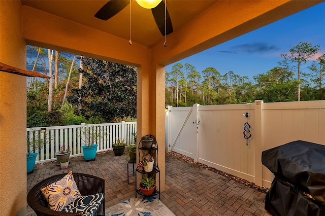 patio terrace at dusk featuring grilling area and ceiling fan