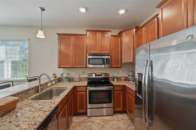 kitchen with light stone countertops, sink, hanging light fixtures, and appliances with stainless steel finishes