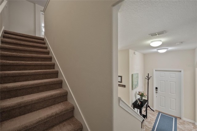 stairway featuring a textured ceiling