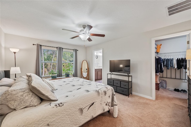 carpeted bedroom featuring a walk in closet, ensuite bathroom, a closet, and ceiling fan