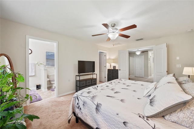 carpeted bedroom with ensuite bath and ceiling fan