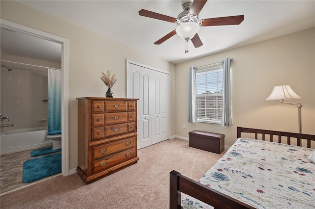 bedroom with ceiling fan, ensuite bath, light carpet, and a closet