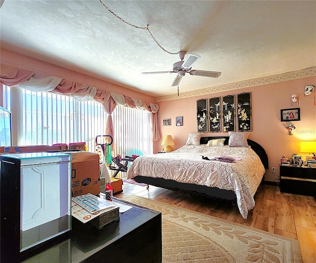 bedroom featuring hardwood / wood-style flooring, ceiling fan, and multiple windows