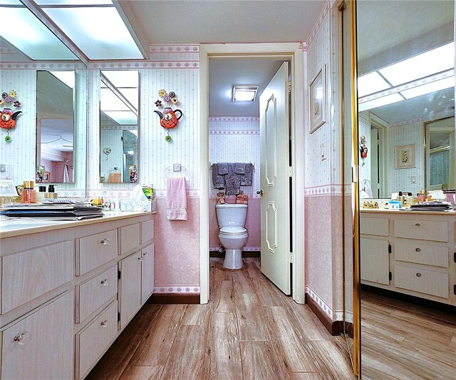 4116 SE 20th Pl Unit 102, Cape Coral, FL 33904 - bathroom featuring wallpapered walls, wood finished floors, vanity, and toilet