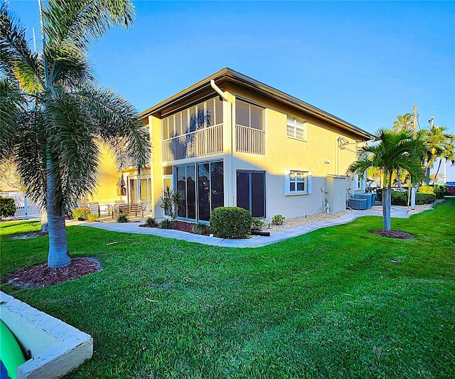 rear view of property featuring a sunroom, central AC unit, and a yard