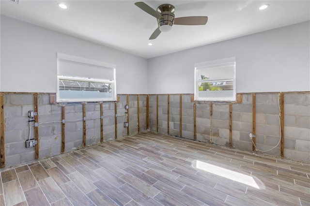 unfurnished room featuring ceiling fan and tile walls