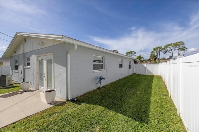 view of home's exterior featuring a lawn, cooling unit, and french doors