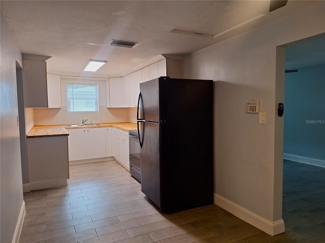 kitchen with black appliances, light hardwood / wood-style floors, white cabinets, and sink