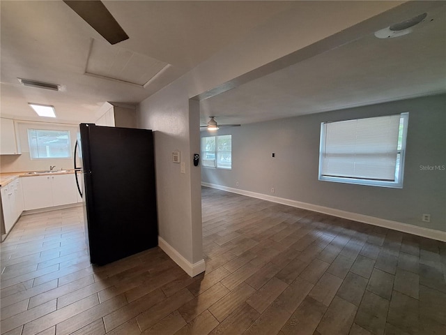 kitchen featuring white cabinets, hardwood / wood-style flooring, black fridge, and ceiling fan