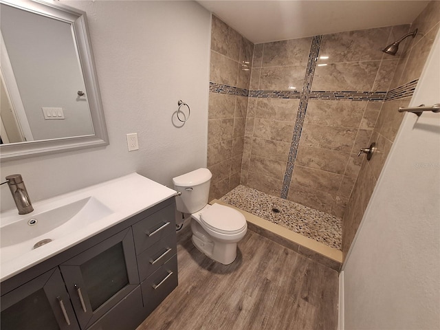 bathroom featuring tiled shower, hardwood / wood-style floors, vanity, and toilet