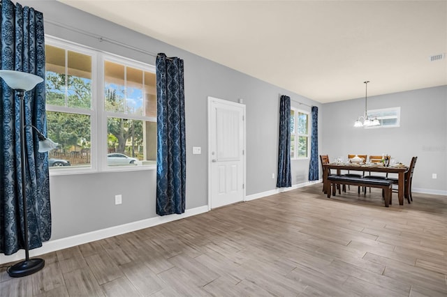 dining area with hardwood / wood-style floors, a wealth of natural light, and a chandelier