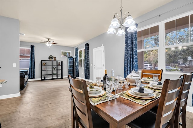 dining room featuring ceiling fan with notable chandelier, light wood-type flooring, and a healthy amount of sunlight