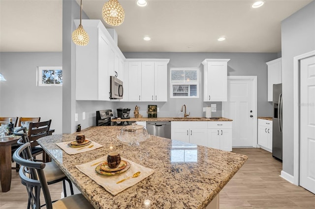 kitchen with sink, a breakfast bar area, light hardwood / wood-style flooring, decorative light fixtures, and stainless steel appliances