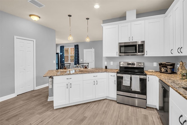 kitchen featuring white cabinets, stainless steel appliances, light hardwood / wood-style flooring, and hanging light fixtures