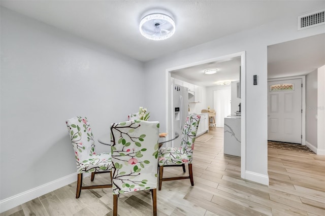 sitting room with light wood-type flooring, visible vents, and baseboards