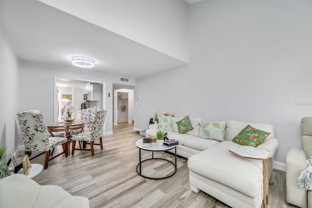 living room with light wood-style flooring, visible vents, and baseboards