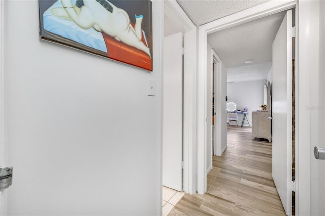 corridor featuring a textured ceiling and wood finished floors