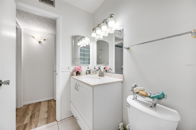 bathroom featuring visible vents, a textured ceiling, toilet, and vanity