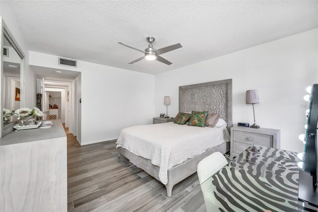 bedroom featuring a textured ceiling, ceiling fan, wood finished floors, and visible vents