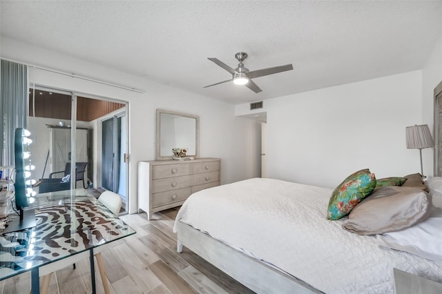 bedroom featuring a ceiling fan, light wood-type flooring, visible vents, and a textured ceiling