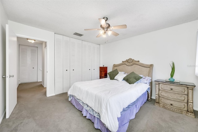 bedroom with visible vents, ceiling fan, carpet, a textured ceiling, and a closet