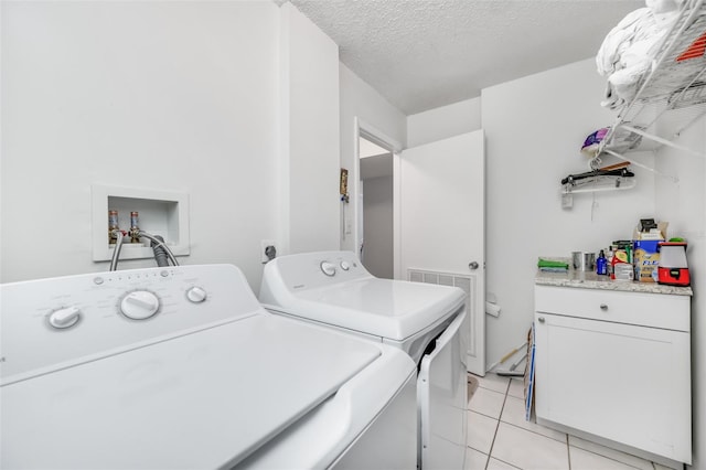 laundry area featuring light tile patterned floors, a textured ceiling, independent washer and dryer, and cabinet space