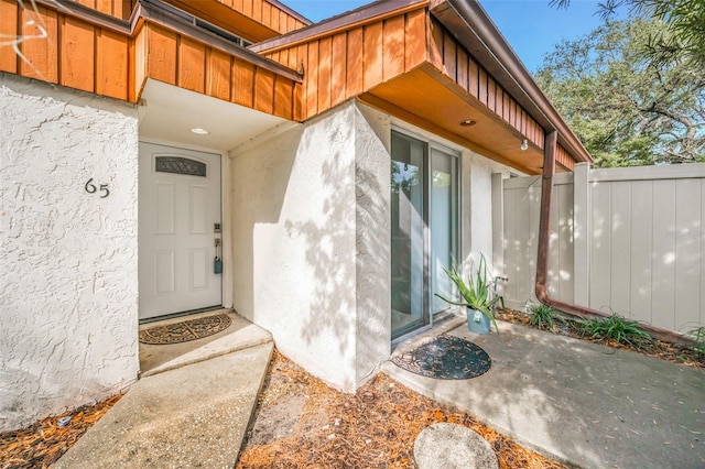 view of exterior entry with a patio, fence, and stucco siding