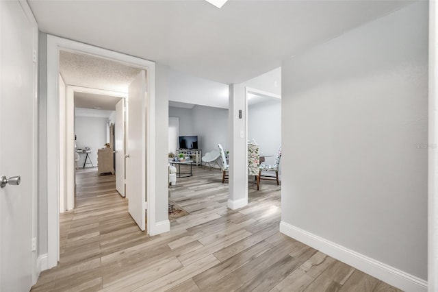 hall with baseboards and light wood finished floors