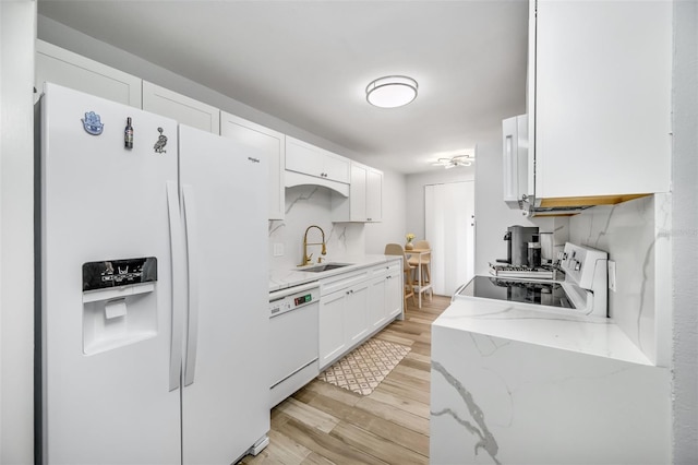 kitchen featuring light stone counters, white appliances, a sink, white cabinets, and light wood-type flooring