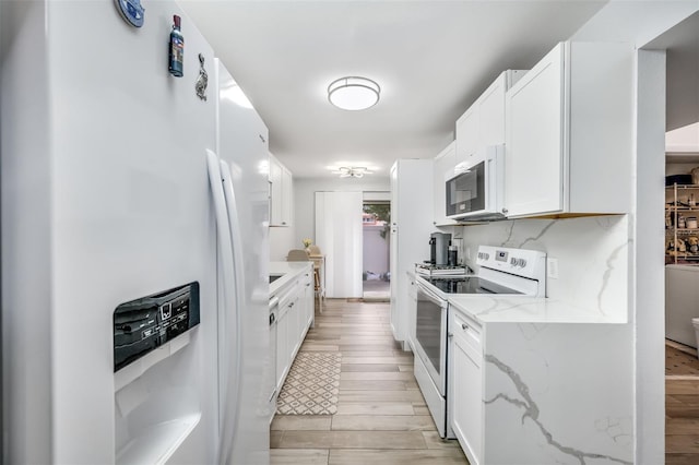 kitchen featuring light wood-style floors, white appliances, white cabinetry, and decorative backsplash